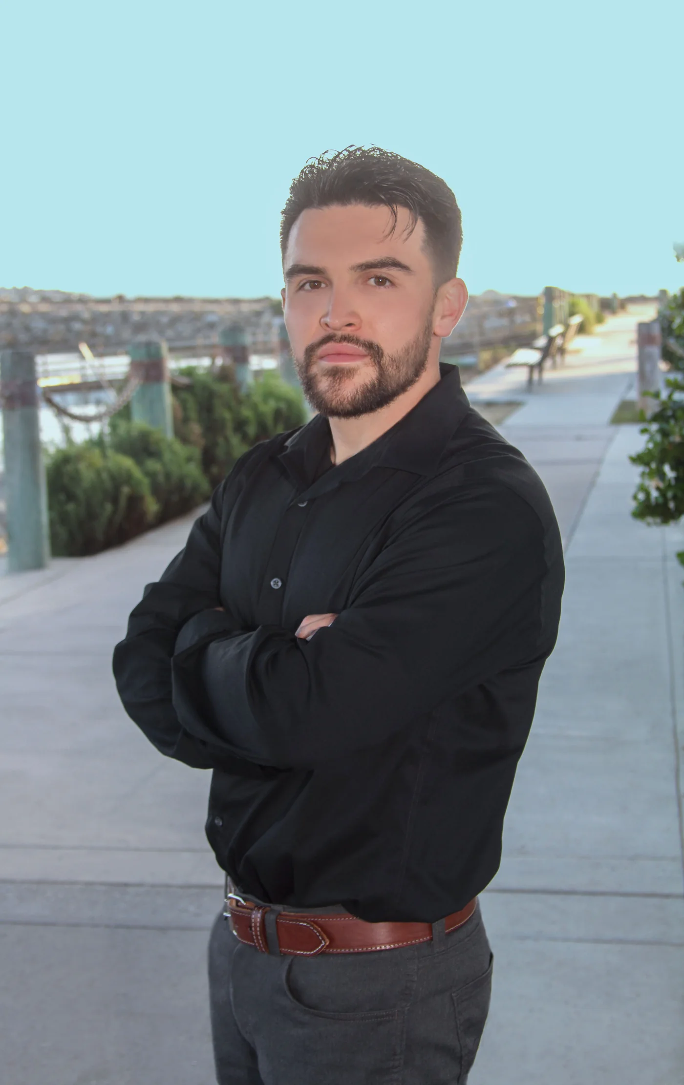 Jorge Lopez Jr., REALTOR®, standing with arms crossed on a waterfront walkway